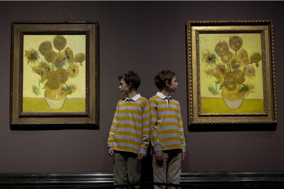 Twins Edgar, left, and Gabriel, aged 10, pose for photographers beside two versions of Dutch-born painter Vincent van Gogh's "Sunflowers", the left one from 1888 and the right one from 1889, during a photocall at the National Portrait Gallery in London, Friday, Jan. 24, 2014. The two paintings are being reunited in London for the first time in 65 years, with the 1889 version on loan from the Van Gogh Museum in Amsterdam. They will be displayed together until April 27. (AP Photo/Matt Dunham)