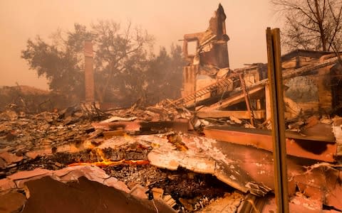 The charred remains of a burned out home are seen during the Woolsey fire in Malibu, California - Credit: AP