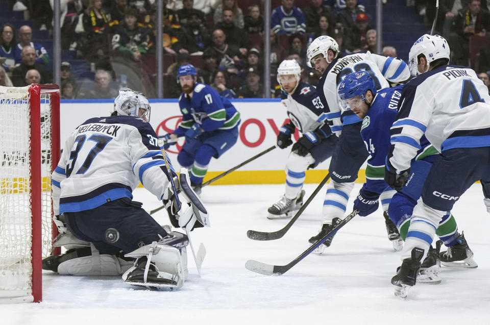 Vancouver Canucks' Pius Suter (24) puts a shot wide of the net behind Winnipeg Jets goalie Connor Hellebuyck (37) during the first period of an NHL hockey game in Vancouver, British Columbia, Saturday, Feb. 17, 2024. (Darryl Dyck/The Canadian Press via AP)