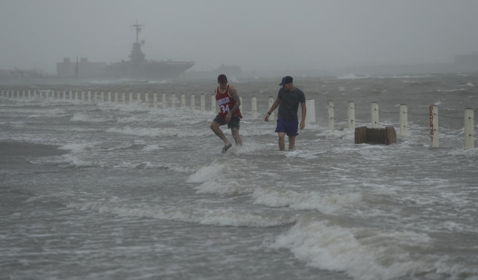 Two men walk on a flooded road as Hurricane Hanna makes landfall, Saturday, July 25, 2020, in Corpus Christi, Texas. The National Hurricane Center said Saturday morning that Hanna's maximum sustained winds had increased and that it was expected to make landfall Saturday afternoon or early evening. (AP Photo/Eric Gay)