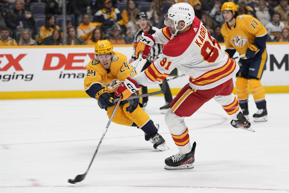 Calgary Flames center Nazem Kadri (91) shoots the puck past Nashville Predators defenseman Spencer Stastney (24) during the first period of an NHL hockey game Wednesday, Nov. 22, 2023, in Nashville, Tenn. (AP Photo/George Walker IV)