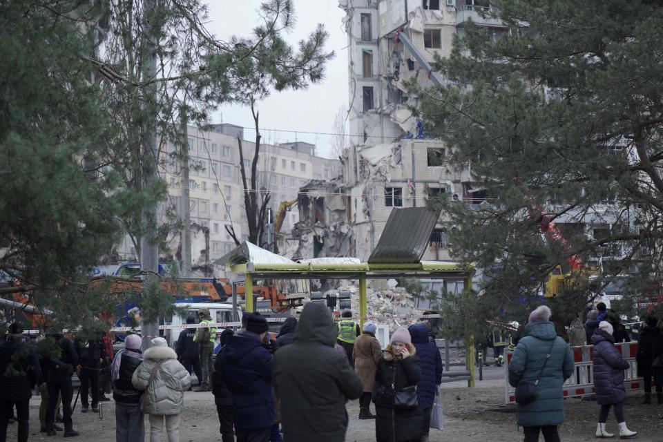 Local residents look at rescuers working on the building (AFP via Getty Images)