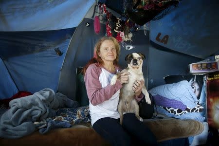 Kathleen Fox, 54, poses for a portrait with her dog Pork Chop by the tent in which she lives, under a freeway on a street in Los Angeles, California, United States, November 13, 2015. REUTERS/Lucy Nicholson