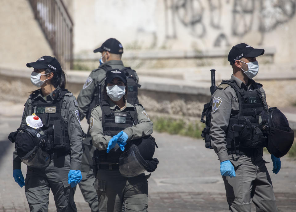 Israeli border police wear face masks after dispersing ultra-Orthodox Jewish children burning leavened items in final preparation for the Passover holiday in the Orthodox neighborhood of Mea Shearim in Jerusalem, Wednesday, April 8, 2020. Jerusalem authorities have said they will gather the bread and burn it in a big bonfire in one location to avoid large gatherings. But, some in the Mea Shearim neighbourhood shunned the orders. Many of Israel's ultra-Orthodox residents, obeying their religious leaders, have ignored pleas to stay home in the face of the coronavirus threat. (AP Photo/Ariel Schalit)