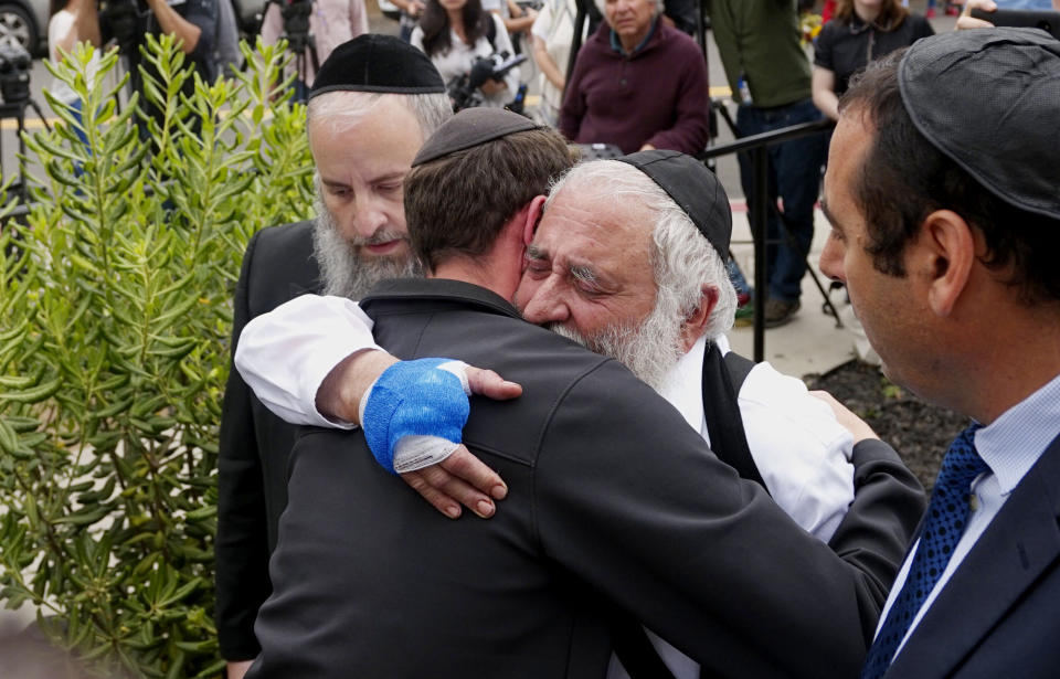 Executive Director Rabbi Ysrael Goldstein (2nd R), who was shot in the hands, hugs his congregants after a press conference outside the Chabad of Poway Synagogue on April 28, 2019 in Poway, California. - A rabbi who carried on preaching despite being wounded in the latest deadly shooting at a US synagogue said on April 28 that Jews would not be intimidated by the "senseless hate" of anti-semitism. (Photo by SANDY HUFFAKER / AFP)        (Photo credit should read SANDY HUFFAKER/AFP/Getty Images)