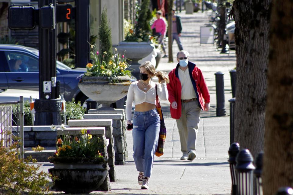 Residents wearing masks walk in downtown Lake Oswego, Ore., on Sunday. Tens of thousands of Oregon residents are angry about a proposal to make permanent an emergency rule that requires masks and social distancing in the state’s businesses and schools to prevent the spread of COVID-19.