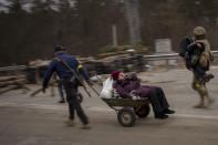 A Ukrainian soldier and a militia man help a fleeing family crossing the Irpin river in the outskirts of Kyiv, Ukraine, Saturday, March 5, 2022. (AP Photo/Emilio Morenatti)