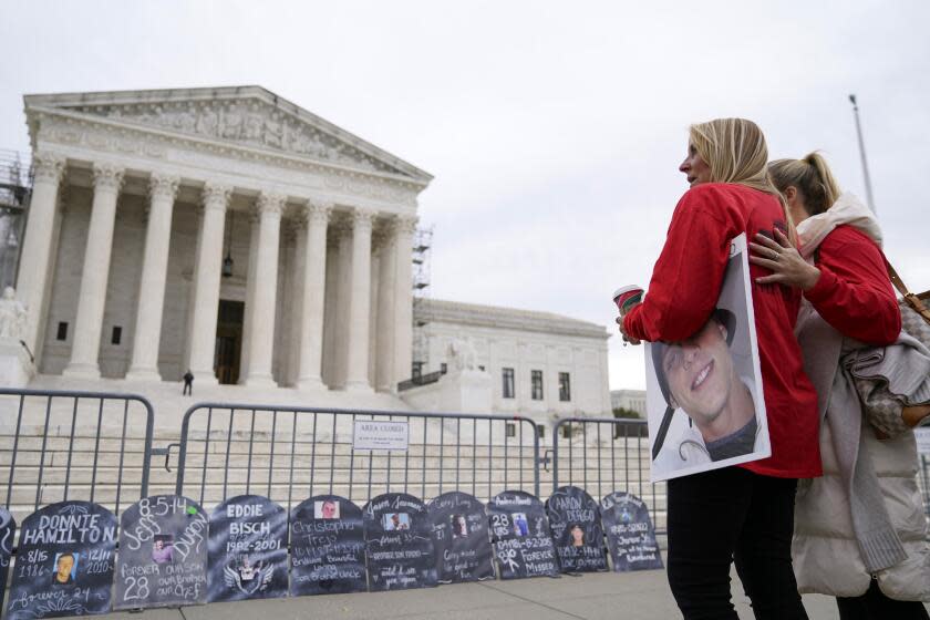 Jen Trejo holds a photo of her son Christopher as she is comforted outside the Supreme Court Monday, Dec. 4, 2023, in Washington. Her son was 32 when he died and she said about Purdue Pharma and the Sackler family, "You can't just kill my child and just pay a fine." The Supreme Court is wrestling with a nationwide settlement with OxyContin maker Purdue Pharma that would shield members of the Sackler family who own the company from civil lawsuits over the toll of opioids. (AP Photo/Stephanie Scarbrough)