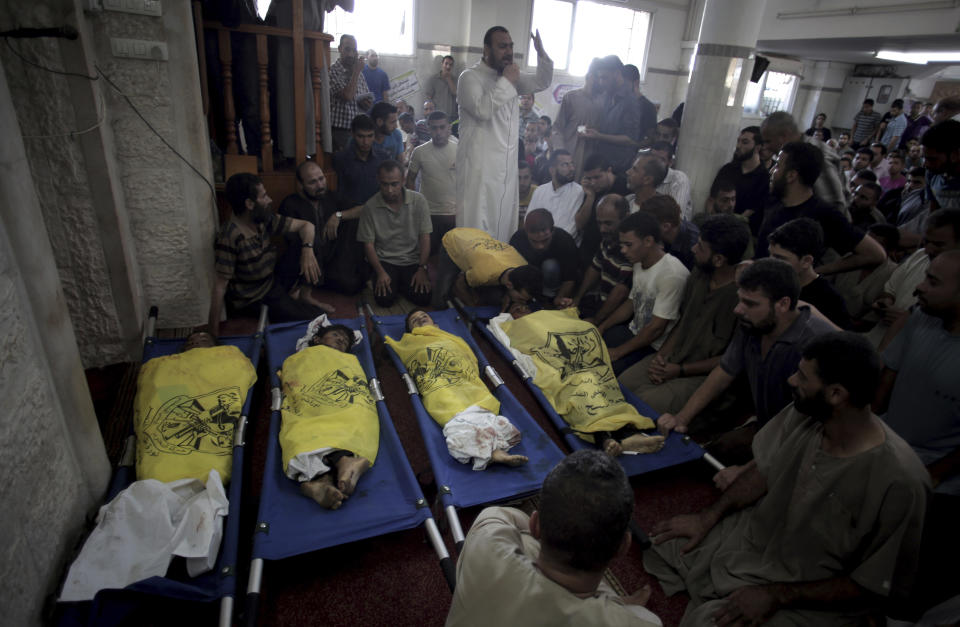 FILE - Palestinians mourn over the lifeless bodies of four boys from the same extended Bakr family, covered with yellow flags of Fatah movement, in the mosque during their funeral in Gaza City, July 16, 2014. Israel’s Supreme Court on Sunday, April 24, 2022 rejected a request to reopen an investigation into the deaths of the four Palestinian children who were killed by an Israeli airstrike while playing on the beach in the Gaza Strip during a 2014 war. (AP Photo/Khalil Hamra)