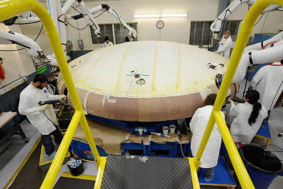 Technicians at Textron in Wilmington, Mass., apply Avcoat ablative material to the composite honeycomb structure attached to the Orion heat shield carrier structure.