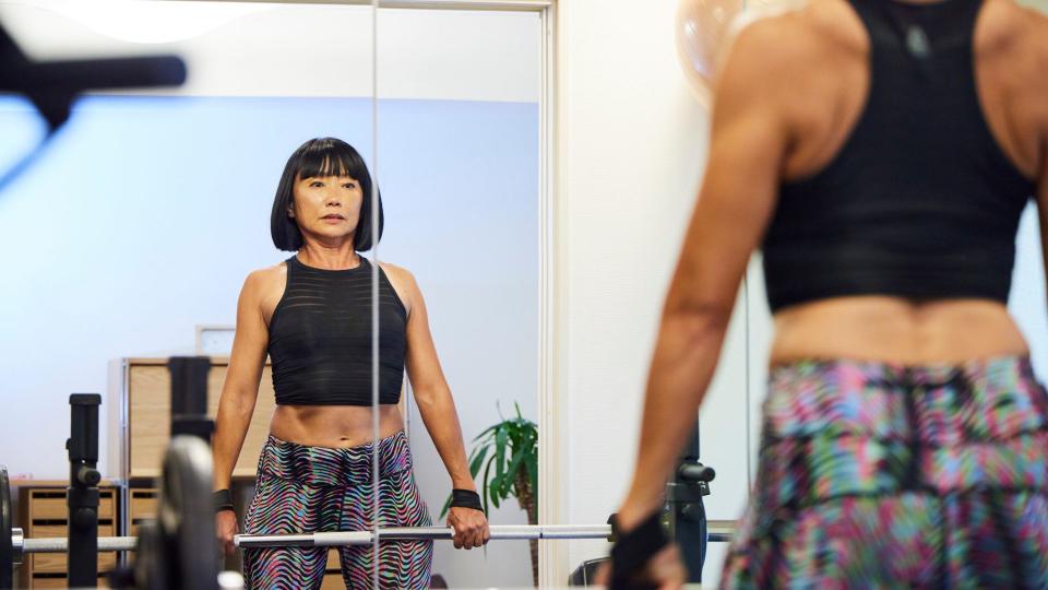 Woman holding a barbell at the top of a deadlift