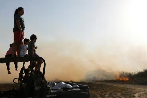 Israeli children watch the progress of a fire on farmland in Kibbutz Beeri after it was set ablaze by a kite launched from across the border in nearby Gaza on June 5, 2018