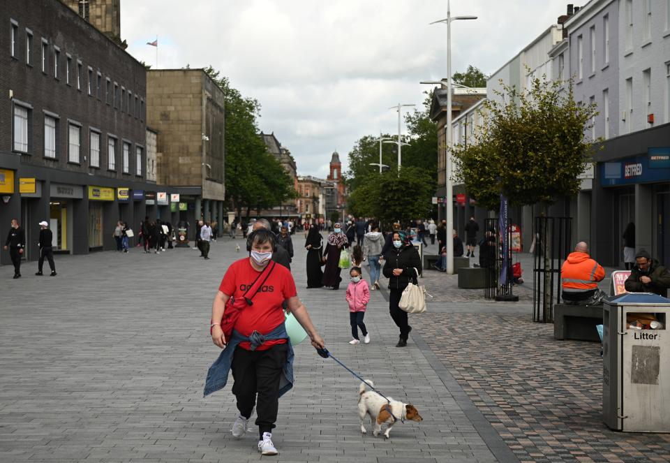 People wear face masks as a precaution against the transmission of COVID-19 as they walk past closed shops in the centre of Bolton, northern England on September 9, 2020, as local lockdown restrictions are put in place due to a spike in cases of the novel coronavirus in the city. - The UK government, which controls health policy in England, imposed tougher restrictions on Bolton, near the northwest city of Manchester, after a "very significant rise" in cases. Bolton was found to have 120 cases per 100,000 people -- the highest in the country. (Photo by Oli SCARFF / AFP) (Photo by OLI SCARFF/AFP via Getty Images)