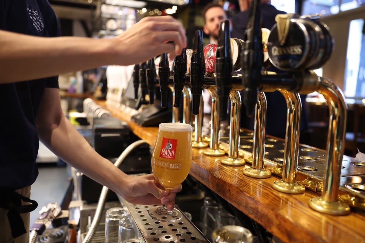 A bar worker pours a pint of lager at a pub in central London in November 2023  (AFP via Getty Images)
