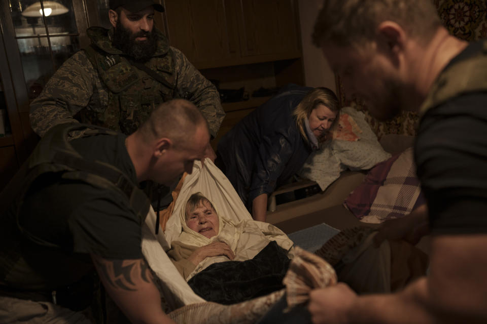 Volunteers evacuate an elderly woman out of her apartment at a frontline neighborhood as Russian bombardments continue in Kharkiv, Ukraine, Monday, April 25, 2022. (AP Photo/Felipe Dana)