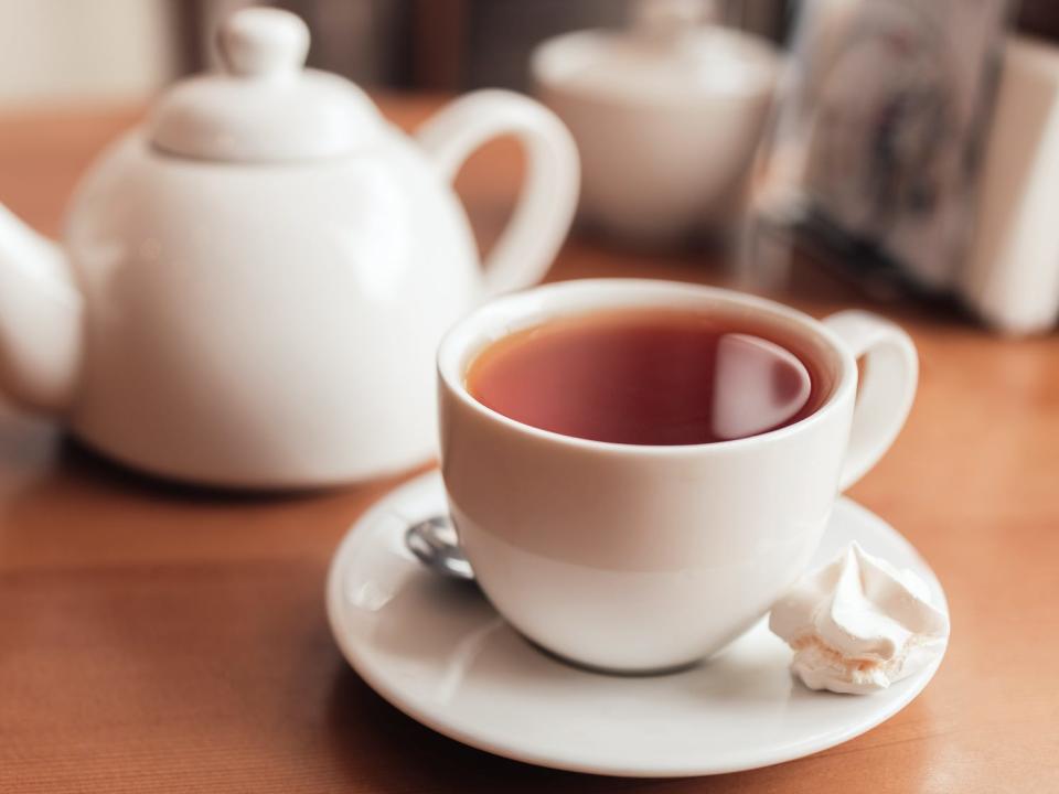 cup of tea in front of a white teapot on a table