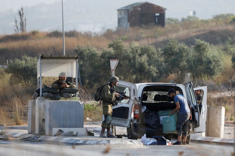 Israeli troops check cars at a checkpoint near a shooting scene in Huwara