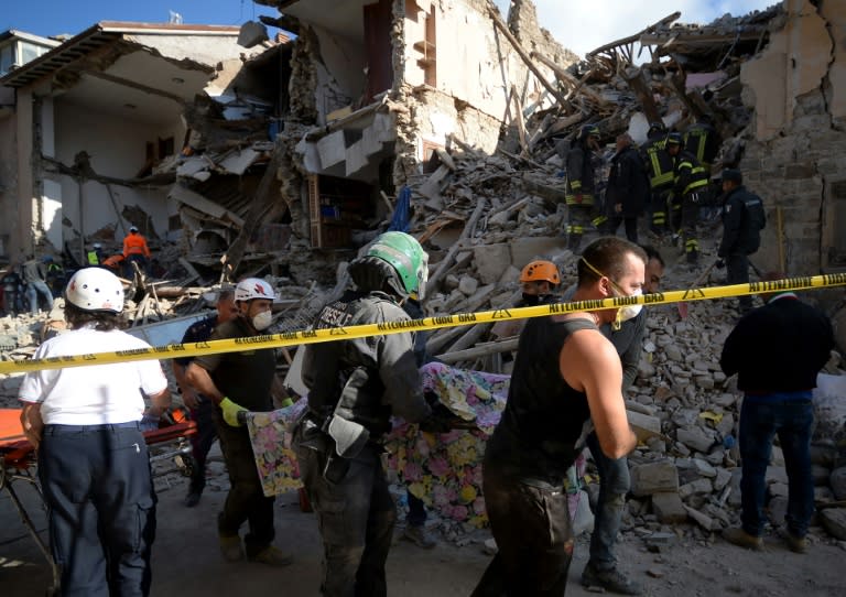 Rescuers carry the body of a victim away from the rubble of buildings in Amatrice, central Italy following the earthquake