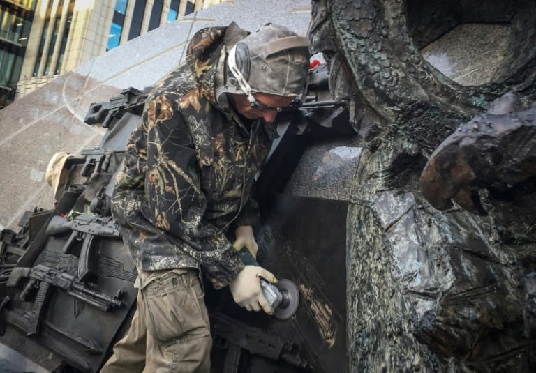 A man uses an angle grinder to obliterate a sketch of a German StG44 rifle from the newly-unveiled monument to Mikhail Kalashnikov, inventor of the Red Army's AK-47 assault rifle, in Moscow on September 22, 2017