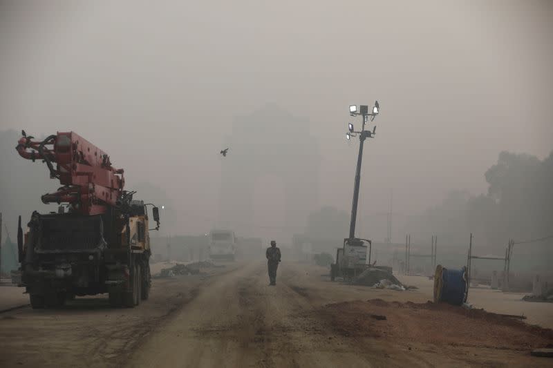 Indian paramilitary soldier walks near India Gate which is shrouded in smog, in New Delhi