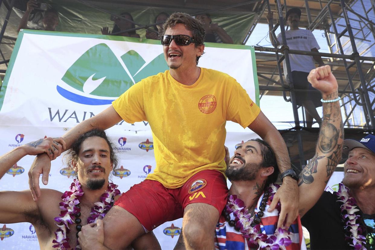 Luke Shepardson, top, is raised up by fellow big wave surfers Landon McNamara, left, and Billy Kemper after winning The Eddie Aikau Big Wave Invitational at Waimea Bay on Sunday, Jan. 22, 2023, on Oahu's North Shore, in Hawaii. (Jamm Aquino/Honolulu Star-Advertiser via AP)