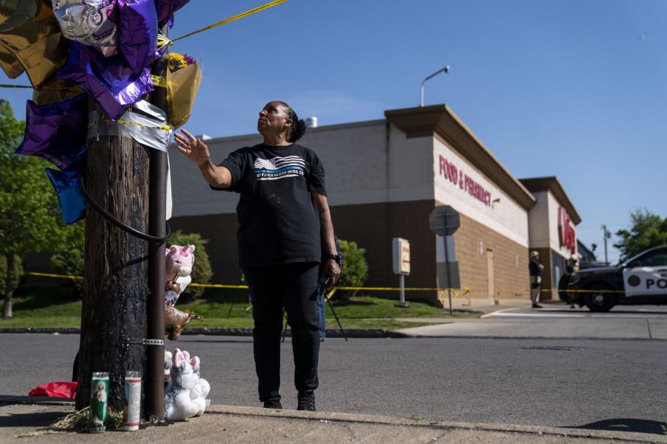 A person readjusts a couple stuffed animals at a makeshift memorial near the Tops Friendly Markets in Buffalo, N.Y.