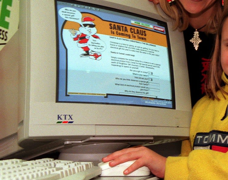 A mother and daughter using an old computer that says "Santa Claus is coming to town"