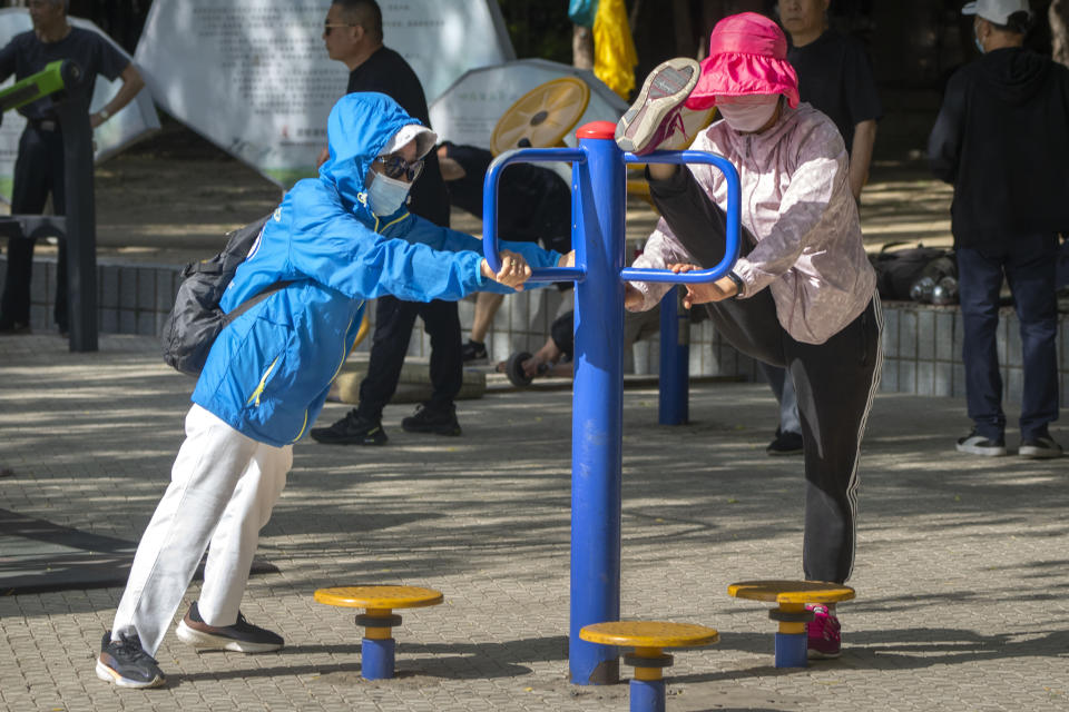 Women wearing face masks use exercise equipment at a public park in Beijing in May 2023.<span class="copyright">Mark Schiefelbein—AP Photo</span>