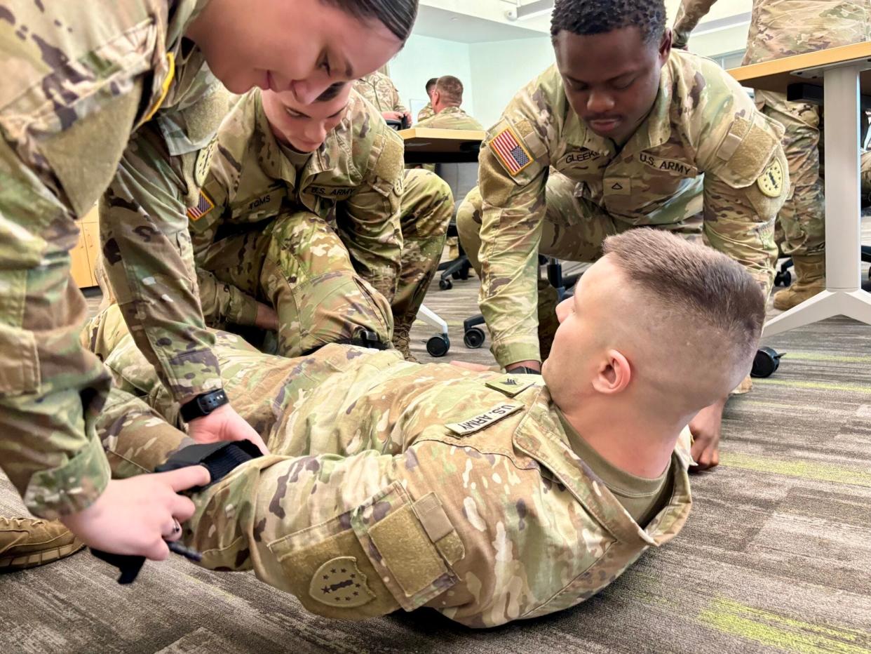 Sgt. Connor Decker plays the role of an injured soldier during training with Pfc. Macenzi Connors, Spc. Jared Toms, and Pfc. Nendoe Gleekia for their mission at the Texas border.