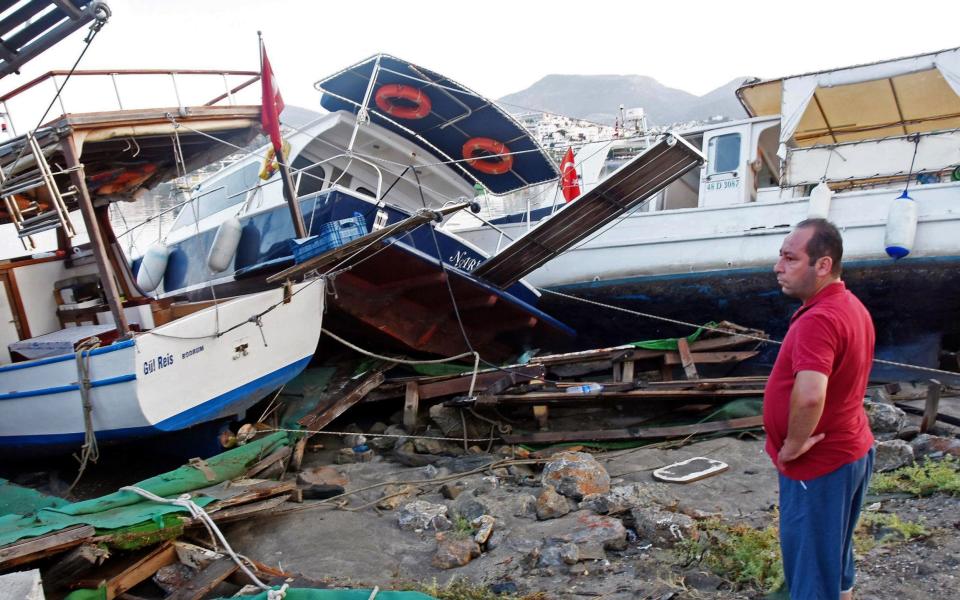 A man looks at damaged boats at a beach following a sea surge - Credit: AFP