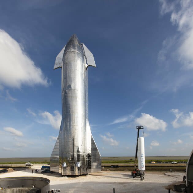 SpaceX’s Starship Mk1 prototype stands alongside a first stage of SpaceX’s Falcon 1 rocket, which had its first successful orbital launch in 2008. If you look closely at this picture from SpaceX’s Boca Chica facility, you can see people to the left of the Starship rocket. (SpaceX via Twitter)