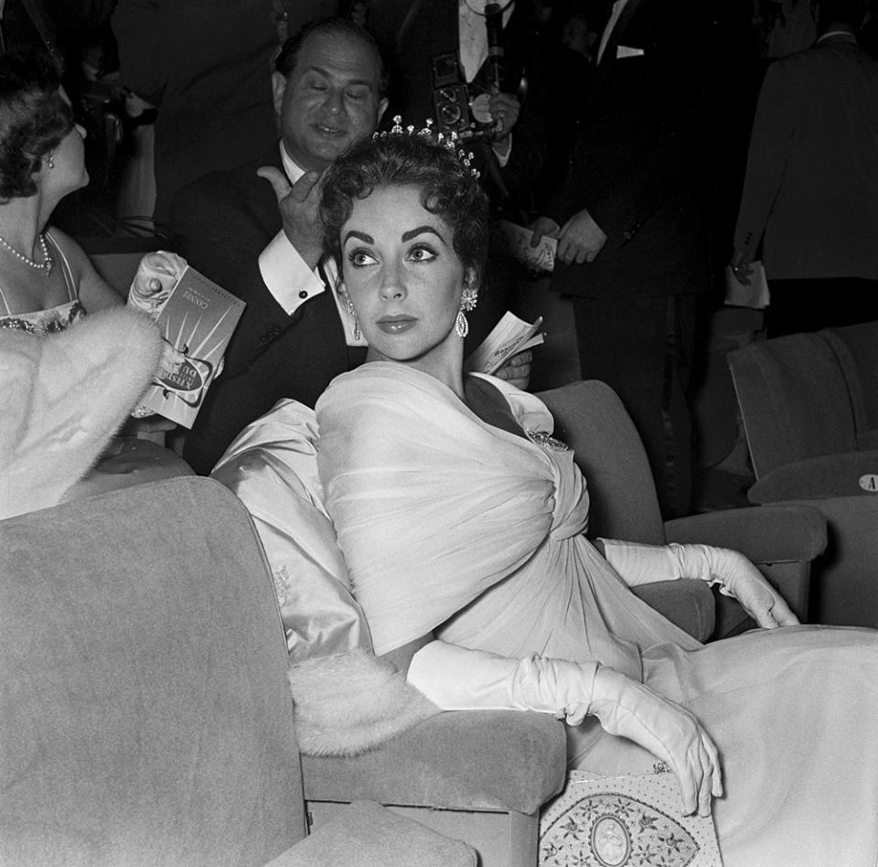 A bejeweled and becrowned Liz Taylor grabs a seat, and all the attention, at the 1957 edition of the festival.