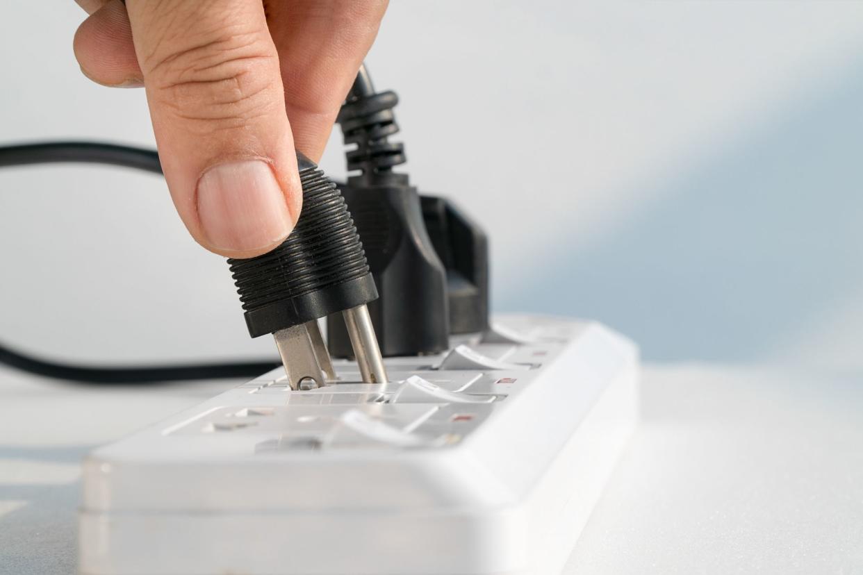 Close up Elderly hand plugging into electrical outlet