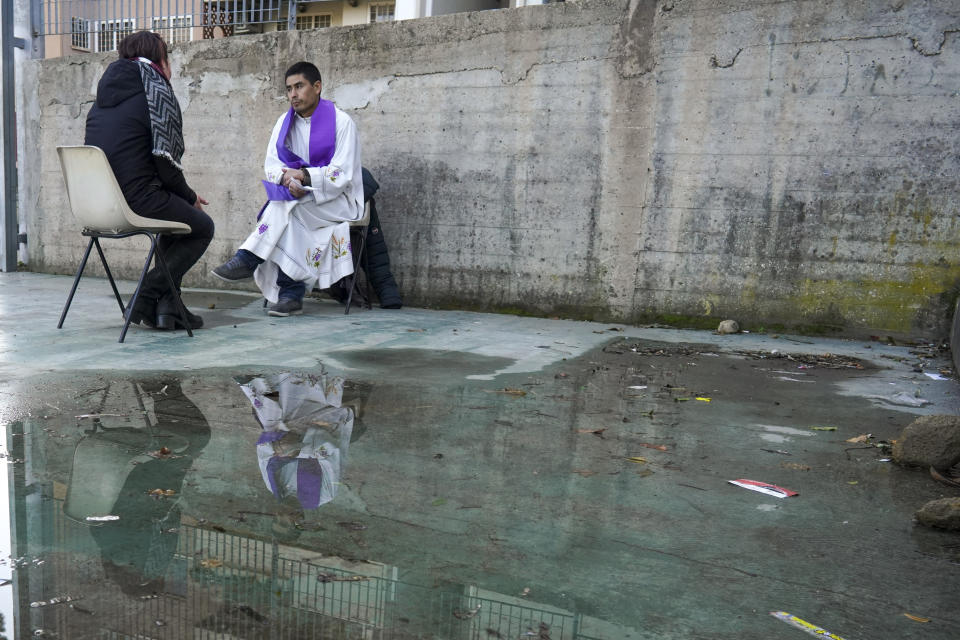 A priest confesses a faithful during a Sunday Mass celebrated in their parish football field.