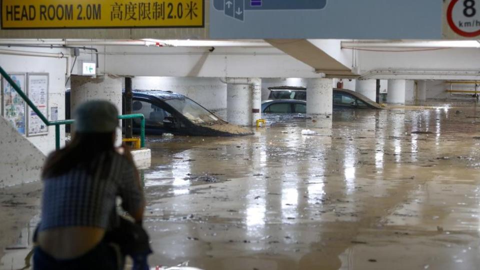 Floodwaters gush into a parking lot in Hong Kong, submerging cars