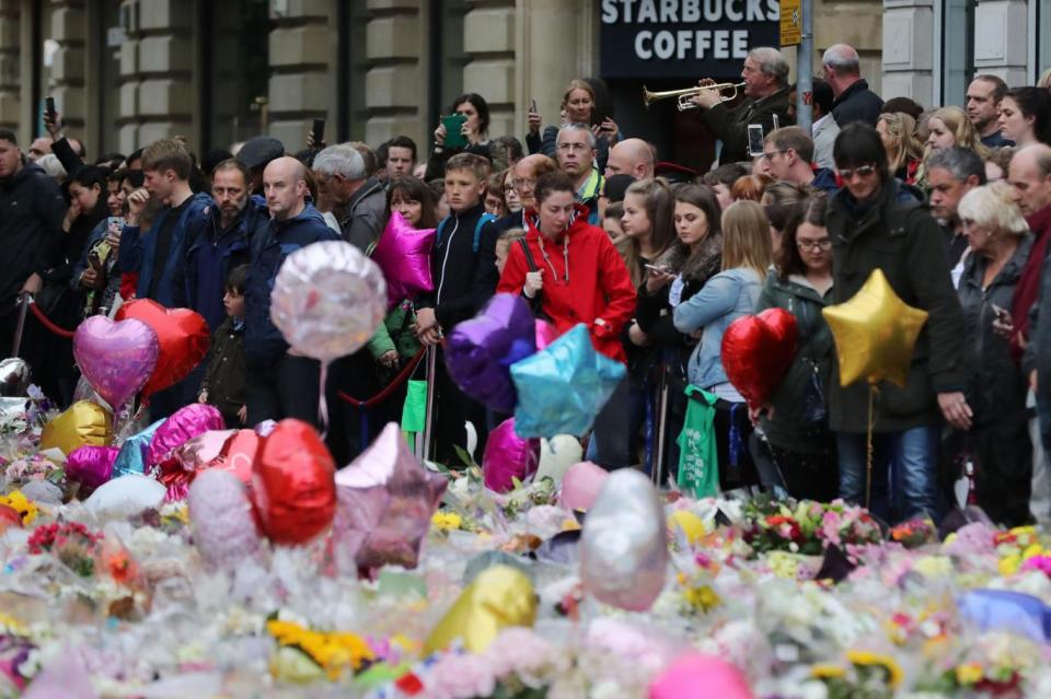 People look at flowers and tributes left in St Ann's Square in Manchester (PA)