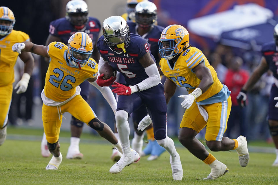 Jackson State wide receiver Shane Hooks (5) runs upfield after a pass reception between Southern University defensive back Rodney Johnson (26) and linebacker Jalan Campbell (56) during the first half of the Southwestern Athletic Conference championship NCAA college football game Saturday, Dec. 3, 2022, in Jackson, Miss. (AP Photo/Rogelio V. Solis)