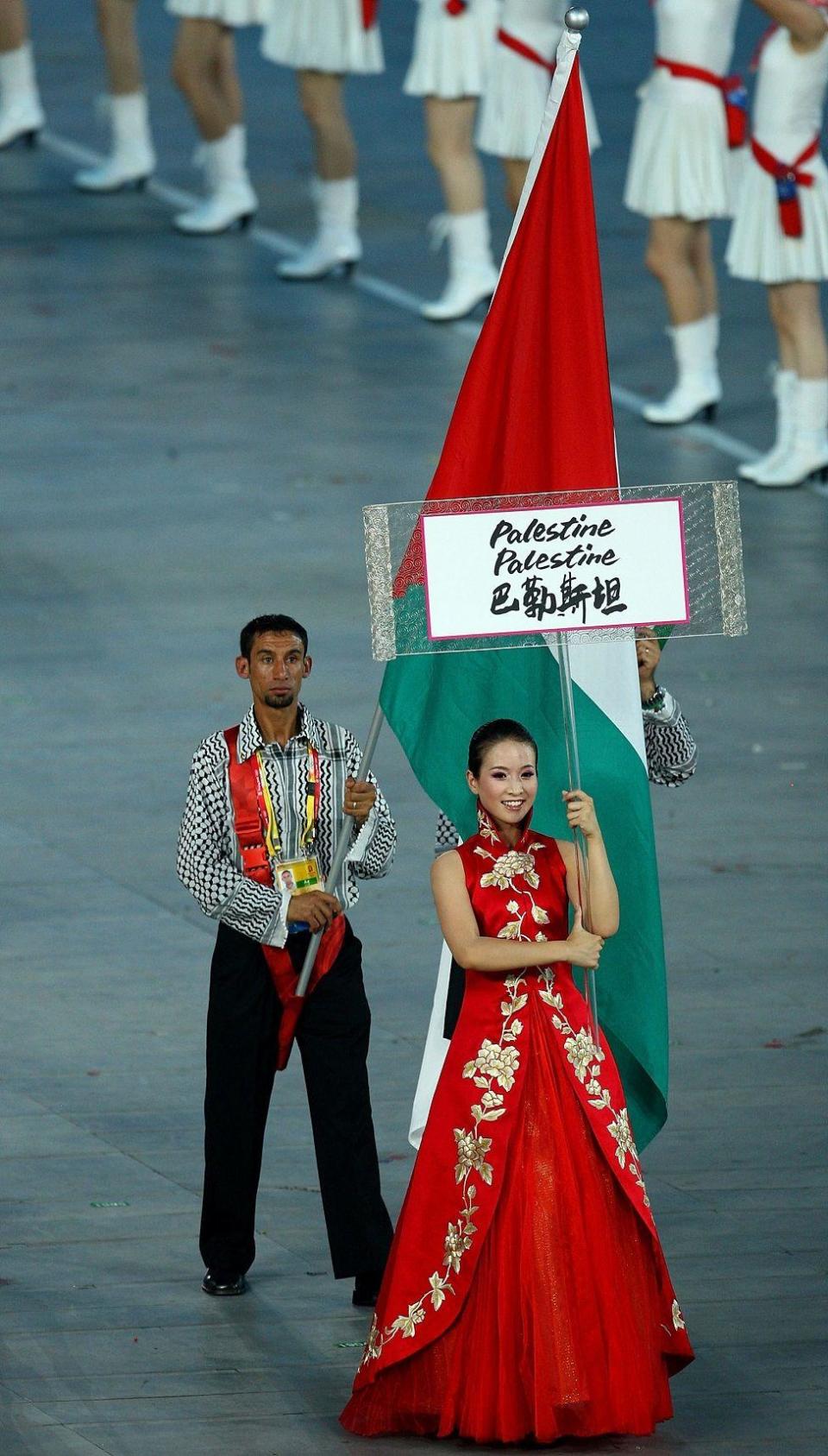 Nader el Masri con la bander palestina siguiendo a una mujer que lleva el cartel que dice Palestine