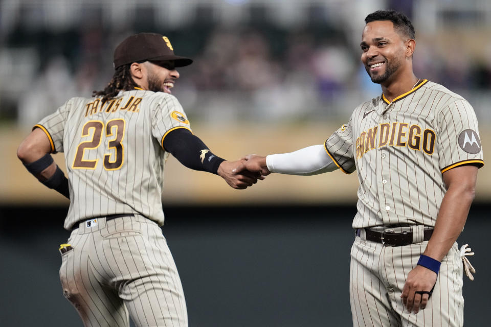 San Diego Padres' Fernando Tatis Jr. (23) and Xander Bogaerts shake hands after the top of the ninth inning of a baseball game against the Minnesota Twins, Tuesday, May 9, 2023, in Minneapolis. (AP Photo/Abbie Parr)