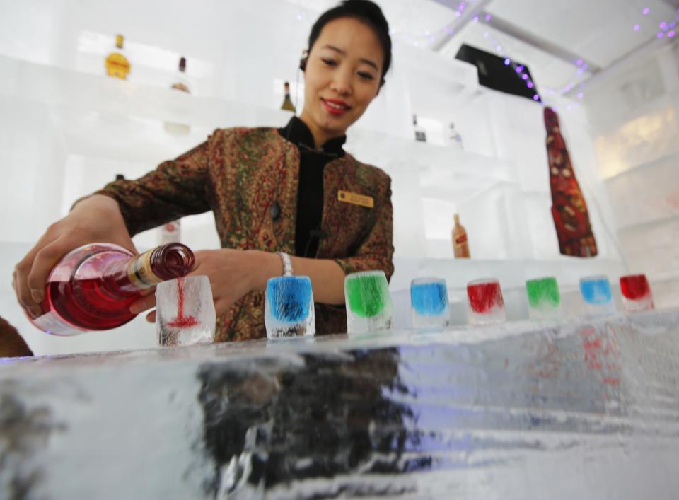 A waitress pours liquor into ice cups on an ice counter during a photo opportunity at the Ice Palace in Shangri-La Hotel in Harbin