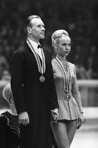 <p> STAFF/AFP via Getty</p> Oleg Protopopov and wife Ludmila Belousova earn gold medals at the 1968 Winter Olympics.