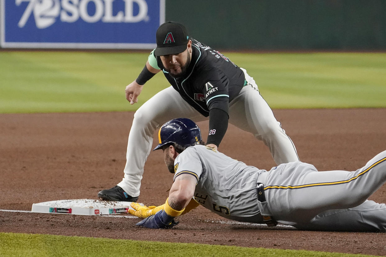 Arizona Diamondbacks third base Eugenio Suárez, top, tags out Milwaukee Brewers' Garrett Mitchell, bottom, after a steal-attempt during the first inning of a baseball game, Saturday, Sept. 14, 2024, in Phoenix. (AP Photo/Darryl Webb)