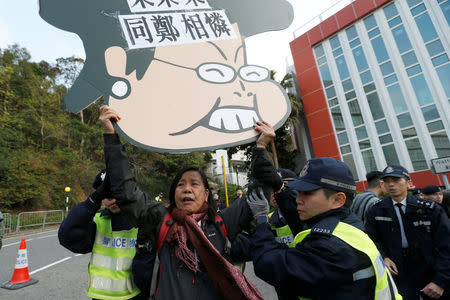 A pro-democracy protester carrying a cartoon of Hong Kong Chief Executive Carrie Lam is taken away by the police before Lam arrives to vote during a Legislative Council by-election in Hong Kong, China March 11, 2018. REUTERS/Bobby Yip