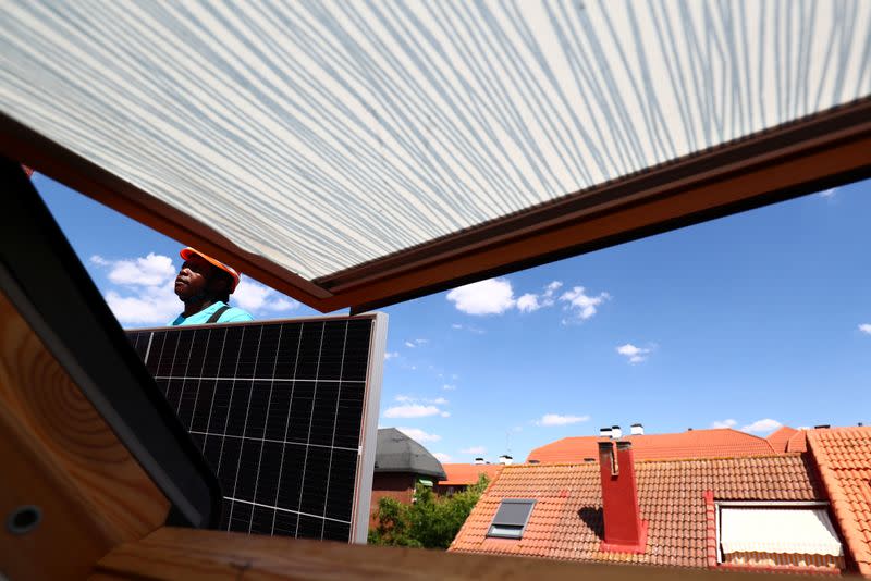 Kauahou, a worker of the installation company Alromar, stands as he sets up solar panels on the roof of a home in Colmenar Viejo