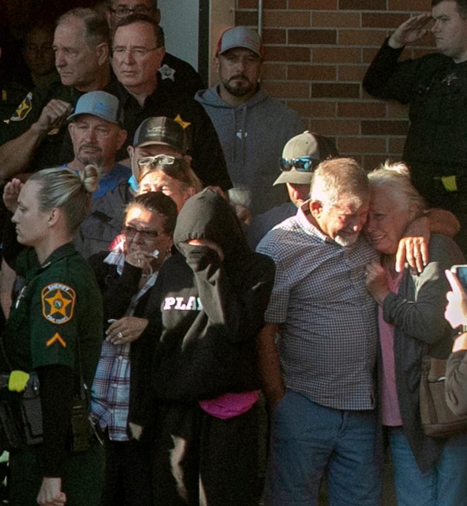 Family members mourn as law enforcement officials escort the body of Polk County Sheriff's Deputy Blane Lane, 21, into an ambulance for transport to the medical examiner's office.