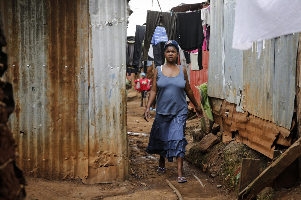 Traditional birth attendant Emily Owino walks down an alley near her home, where she assists women in delivering babies, in the Kibera slum of Nairobi, Kenya Friday, July 3, 2020. Kenya already had one of the worst maternal mortality rates in the world, and though data are not yet available on the effects of the curfew aimed at curbing the spread of the coronavirus, experts believe the number of women and babies who die in childbirth has increased significantly since it was imposed mid-March. (AP Photo/Brian Inganga)