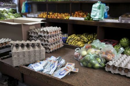 Venezuelan two bolivar banknotes are seen next to some goods at a fruit and vegetable store in Caracas, July 10, 2015. REUTERS/Marco Bello