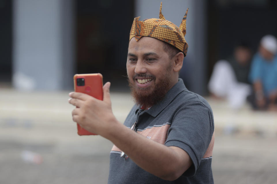 Indonesian militant Umar Patek uses his mobile phone to make a video call in Lamongan, East Java, Indonesia, Tuesday, Dec. 13, 2022. The Islamic militant convicted of making the explosives used in the 2002 Bali bombings that killed over 200 people was paroled last week after serving about half of his original 20-year prison sentence. (AP Photo/Trisnadi)