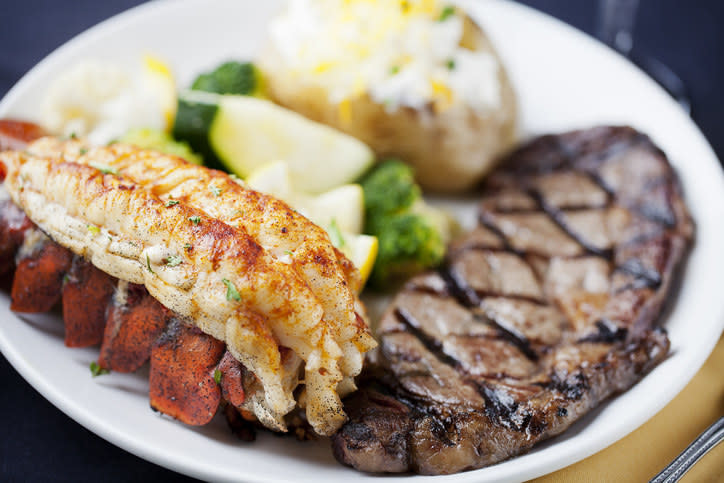Steak and lobster dinner with vegetables and a baked potato