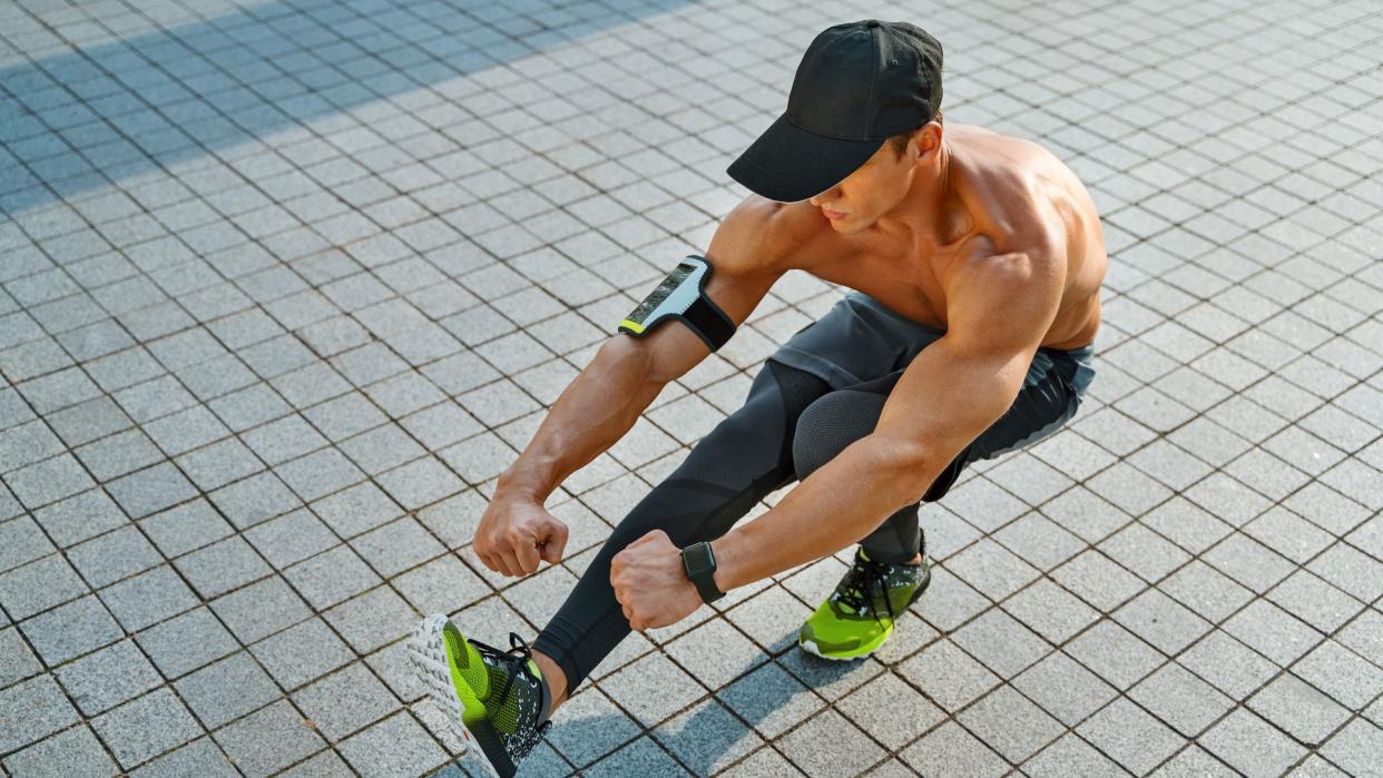  Man outside performing a pistol squat with arms extended and right leg extended in front of him 